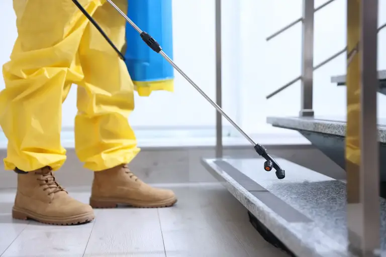 Person in protective suit spraying stairs indoors