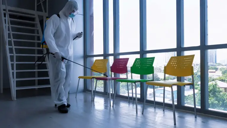 Worker disinfecting chairs in office space