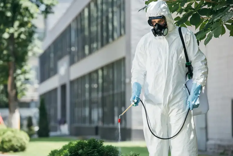 Worker sprays pesticide outside an office building